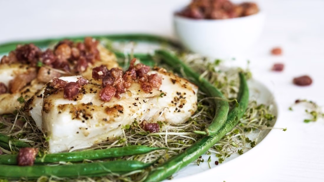 Torsk på seng av bønner, spirer og bacon